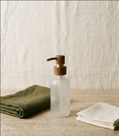 Glass pump bottle beside folded linen cloths